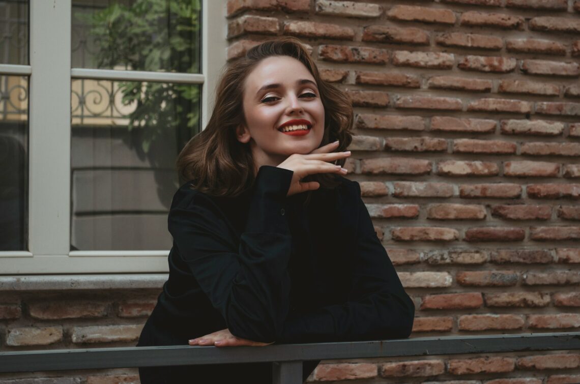 a woman leaning on a rail in front of a brick building